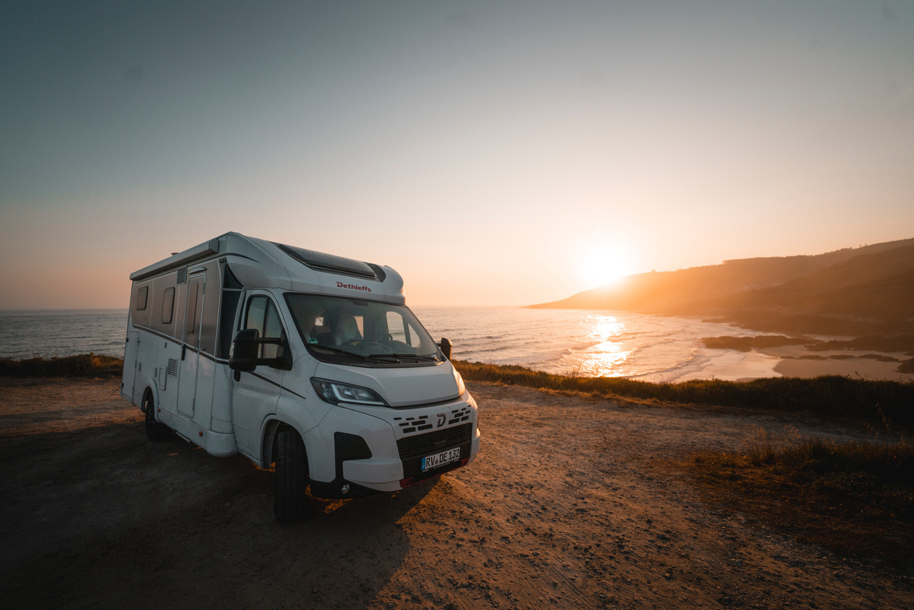 Dethleffs camper aan de kust bij zonsondergang